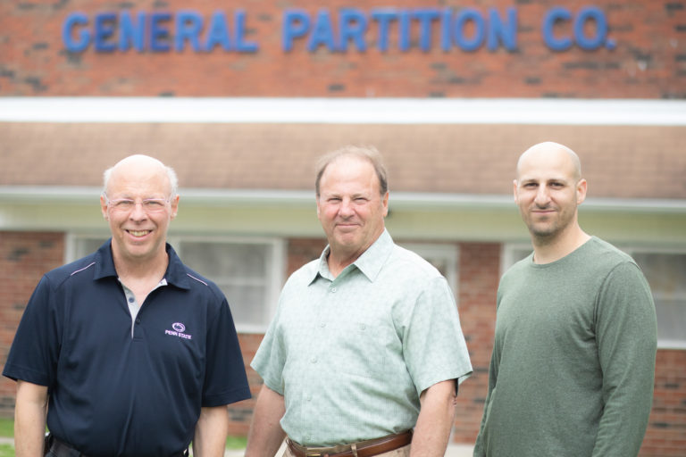 A photo of the General Partition Company family standing together outside their property.